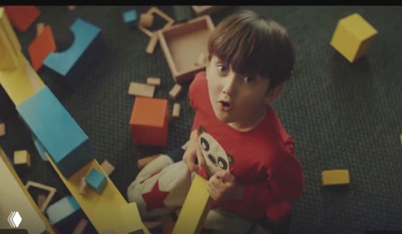 Ребёнок, играющий с яркими кубиками и удивлённым взглядом — визуализация ностальгии и семейных эмоций в рекламе для вызова резонанса.