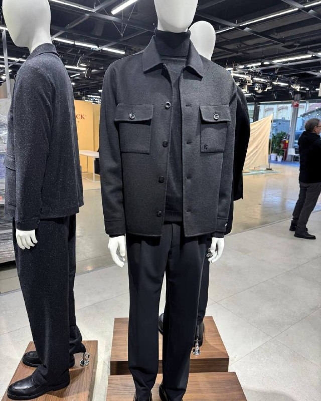 Манекен в тёмно‑сером утеплённом жакете и строгих брюках — сдержанный городской силуэт DIGEL Move, демонстрируемый на выставке мужской моды.