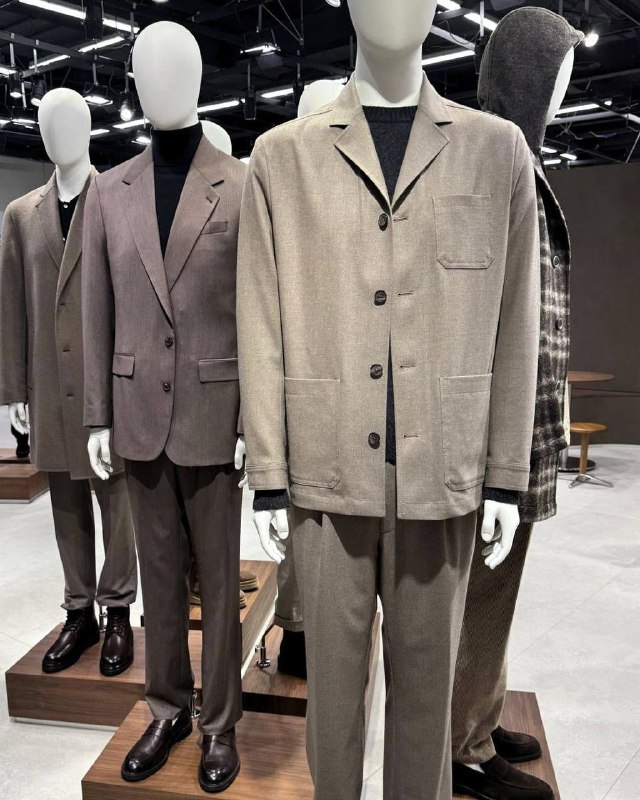 Пара манекенов в светло‑бежевых и серых костюмах DIGEL: просторные пиджаки, свободный крой, классическая обувь — акцент на повседневной элегантности.
