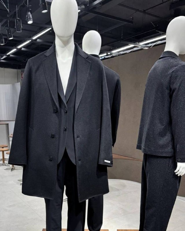 Манекен в чёрном оверсайз‑пальто и костюме DIGEL — контрастная часть экспозиции, подчёркивающая универсальность кроя и вечерние варианты образов на Pitti Uomo.