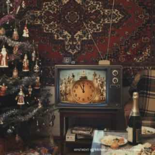 Винтажный телевизор с круглым циферблатом в кадре, рядом новогодняя ёлка, шампанское и праздничная сервировка — атмосфера старого праздника