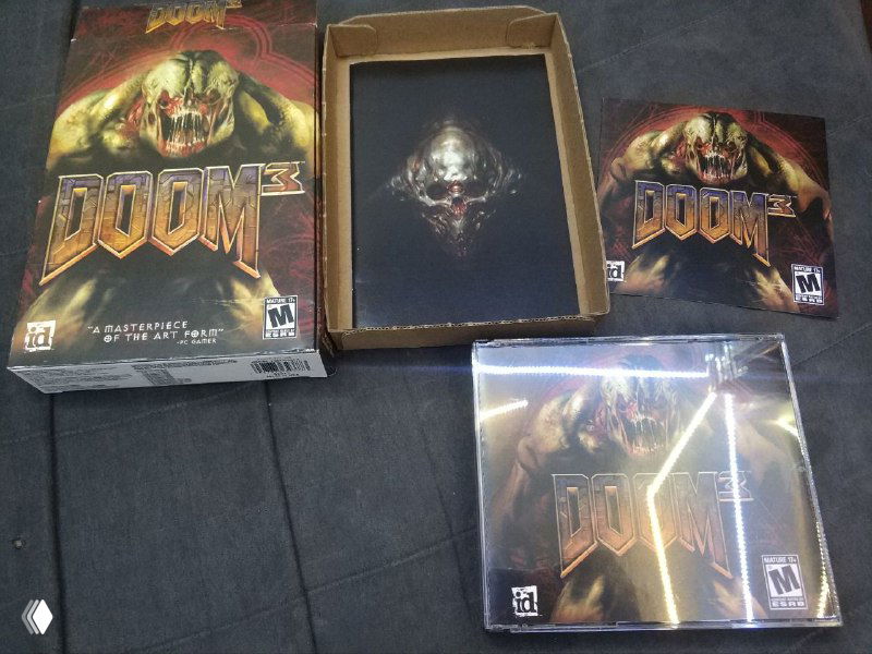 Другая фотография тех же двух коробок Doom 3 с акцентом на пластиковую упаковку и внешний вид дисков для сбора различий.