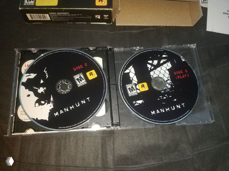 Крупный план двух дисков Manhunt из набора: видно оформление дисков и пластикнутый держатель, характерный для редкого трёхдискового футляра.