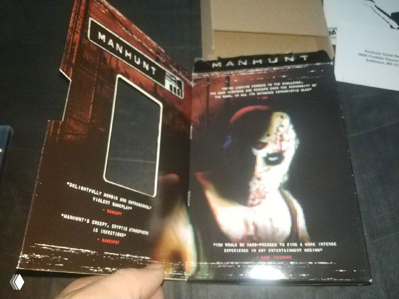 Разворот обложки в стиле VHS с изображением персонажа игры Manhunt — видно окно на коробке и фрагмент внутренней полиграфии издания.