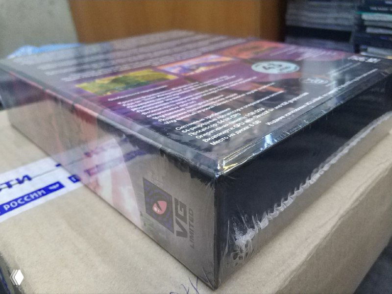 Крупный план торца коллекционного издания Perimeter в заводской обёртке: виден логотип издателя vg-limited и плотная запайка плёнки в условиях домашней съёмки.