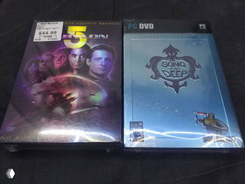 Две запечатанные упаковки: Song of the Deep Collector's Edition в металлической коробке и издание Babylon 5 Season 4 в толстой коробке; передние стороны и отражения плёнки хорошо видны.