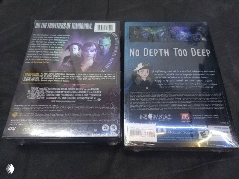 Фото оборотов Song of the Deep и Babylon 5 S4: видны печатные описания, штрихкоды, наклейки с ценой и отражения плёнки — упаковки на тёмной поверхности.