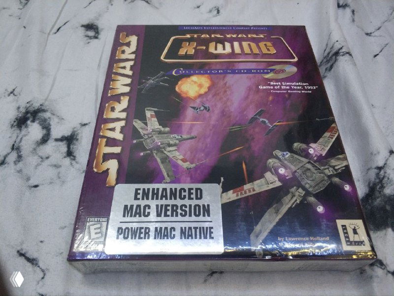 Лицевая сторона коробки Star Wars X-Wing Collector's CD-ROM для Mac в плёнке с наклейкой «Enhanced Mac Version / Power Mac Native», фото демонстрирует версию и состояние упаковки для коллекции.