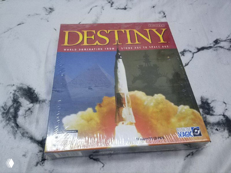 Лицевая фотография запечатанной коробки Destiny с изображением ракеты и заголовком; коробка на столе, заметны блики и плёночная упаковка.