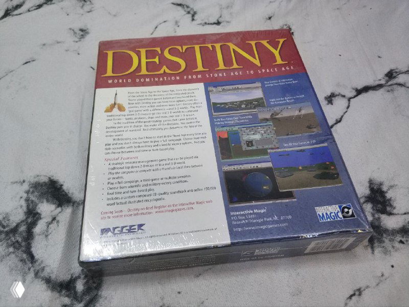 Фото задней стороны коробки Destiny в плёнке: блоки текста, мини‑скриншоты и сведения об издателе видны на светлом фоне столешницы.