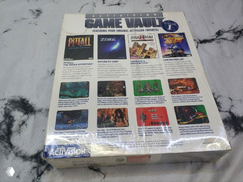 Фото задней стороны Activision Game Vault с перечнем включённых игр и мини‑изображениями; коробка слегка пожелтевшая, видны подписи и иконки игр.