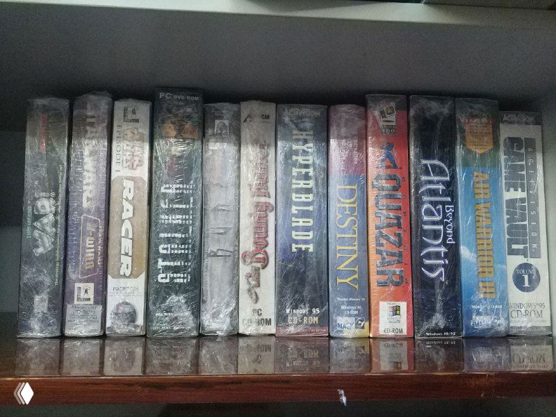 Широкий кадр полки с рядом ретро‑коробок: Pitfall, Return to Zork, Hyper Blade, Destiny, Rune и другие — виден общий спайн‑вид и плотное размещение изданий.