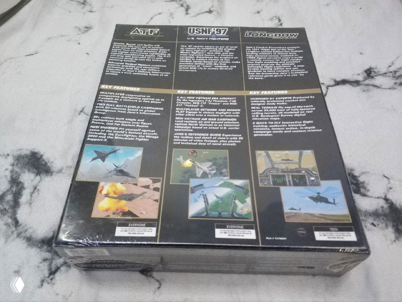 Обратная сторона коробки Jane's Attack Pack с описанием трёх игр и скриншотами, коробка запечатана в плёнку и лежит на столе.