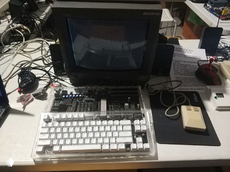 Новодельный MSX в прозрачном акриловом корпусе на демонстрационном столе, видна компактная клавиатура и подключённые периферийные устройства.