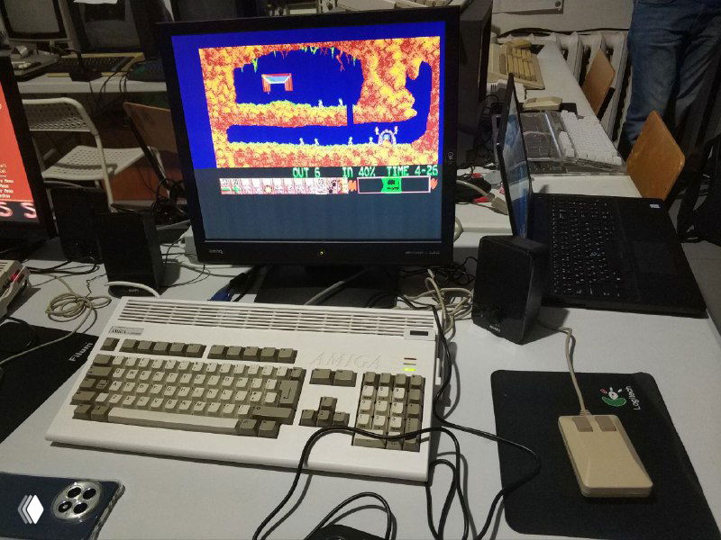 Amiga 1200 в новодельном прозрачном корпусе, на экране запущена игра Lemmings, видно внутреннюю компоновку и кабели на столе.