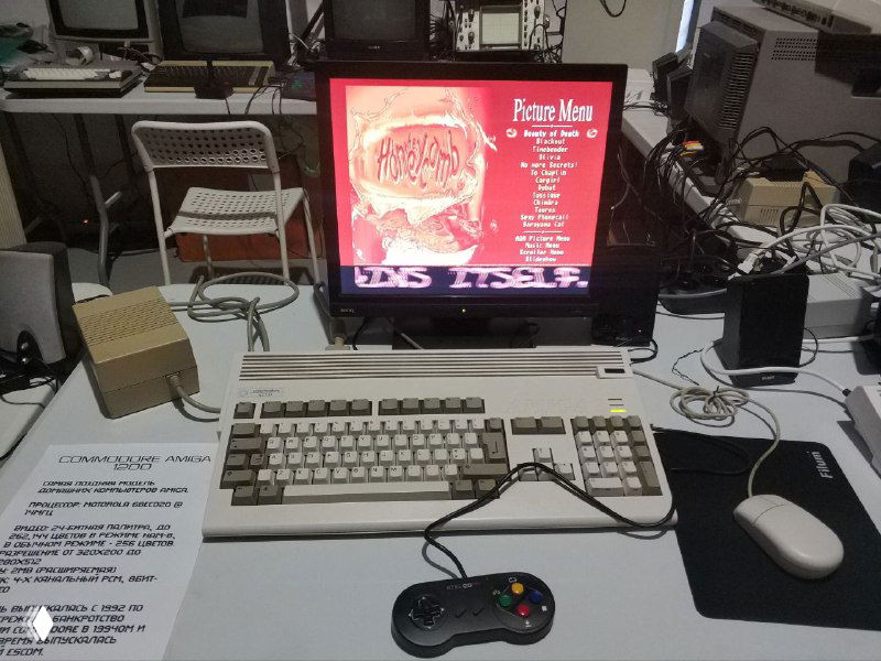 Amiga 1200 в старом оригинальном корпусе в хорошем состоянии, рядом джойстик, монитор и игровые аксессуары — заметна разница корпусов.