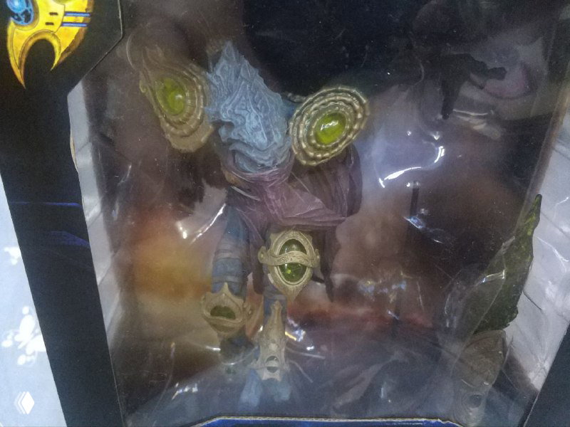 Крупный план фигурки Zeratul внутри прозрачного окна упаковки, видна скульптура протосса, детали брони и оружие через пластик.