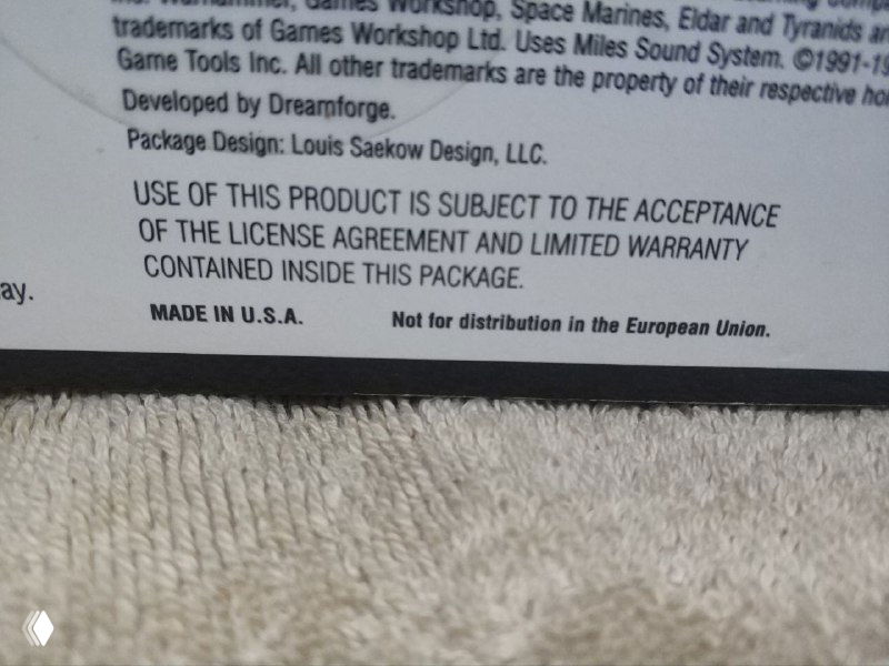 Крупный план нижней части коробки с печатным текстом лицензии и пометкой 'Not for distribution in the European Union', видна текстура картона.