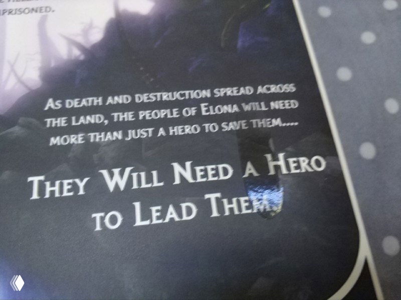 Крупный план текста на странице буклета Nightfall: фраза 'They Will Need A Hero to Lead Them' и след от наклейки на тёмном фоне полиграфии.