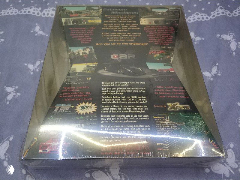 Задняя сторона той же запечатанной коробки Xcar Experimental Racing 1997 года с подписями и скриншотами на обороте, видна прозрачная внешняя упаковка.