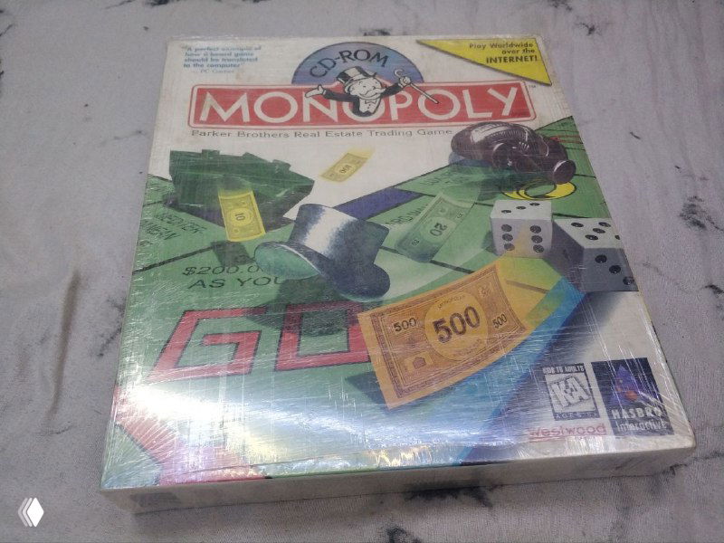 Передняя сторона коробки Monopoly (1996, Hasbro) в запечатанном виде, видна фирменная графика настольной игры на компьютерном издании.