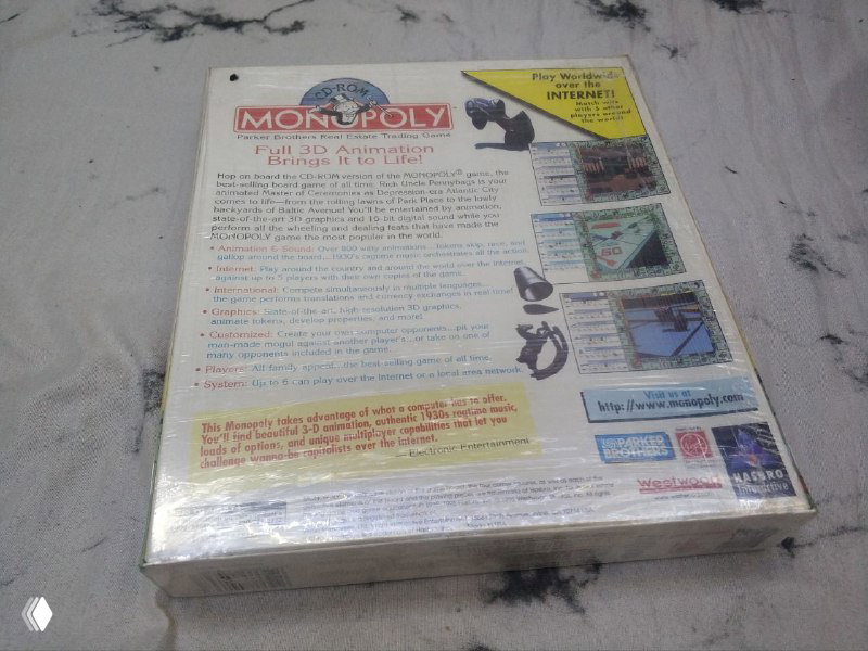 Задняя сторона коробки Monopoly с перечислением функций и системных требований, запечатанная в плёнке и снята на светлом фоне.