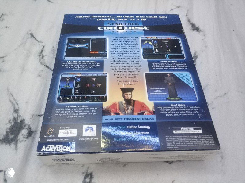 Обратная сторона коробки Star Trek ConQuest Online с описанием и скриншотами; фото сделано на том же светлом фоне, видны технические заметки издания.