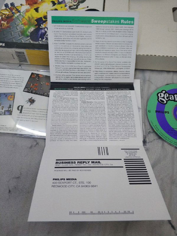 Развернутая регистрационная карта и форма обратной связи Gearheads рядом с коробкой и диском; видны печатные поля, инструкции и штрихкод на фоне упаковки.