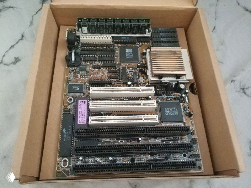 Открытая коробка с материнской платой Zida Tomato: вид сверху на плату с слотами расширения, радиатором и разъёмами.