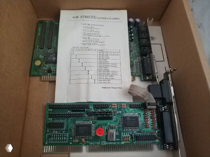 В коробке видны платы, мультиконтроллер и распечатанный мануал по материнской плате, уложенные на картонной подложке.