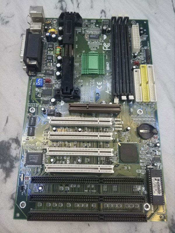 Материнская плата Acorp 6bx67 общий план: слоты расширения, разъёмы на задней панели, видимые следы замены нескольких конденсаторов и отсутсвие пары метизов на RS232.