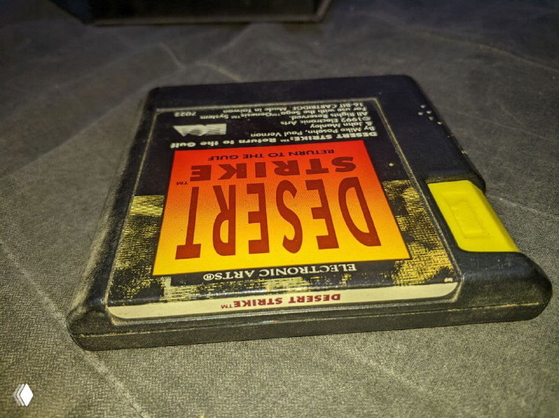 Фон картриджа Desert Strike крупным планом: наклейка с частично стертым изображением и торец картриджа с характерной желтой защёлкой.