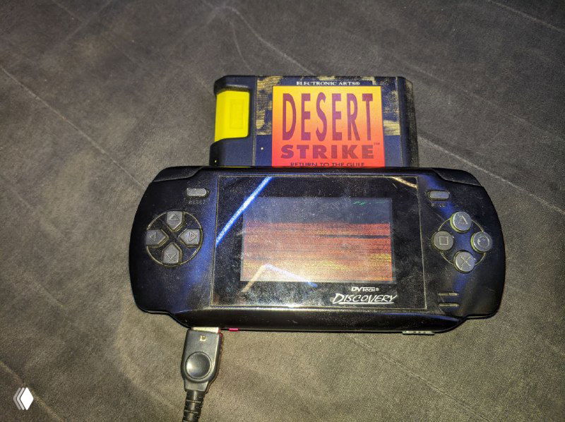 Испытание картриджа Desert Strike в портативной ретро-консоли: картридж вставлен, видна игра на экране и контроллер, вертолёт ещё не пролетел.