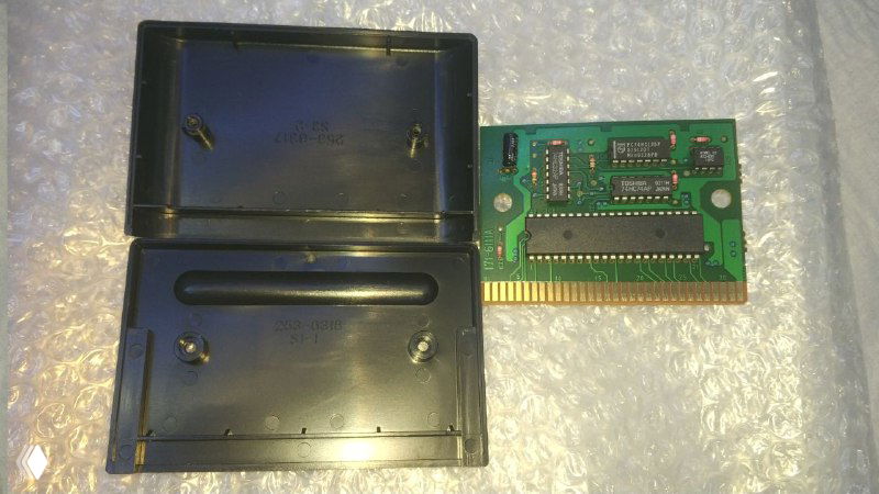 Картридж раскрыт: корпус открыт, плата вынута и показана отдельно — видны контакты картриджа, дорожки и посадочные места для микросхем и батарейки.