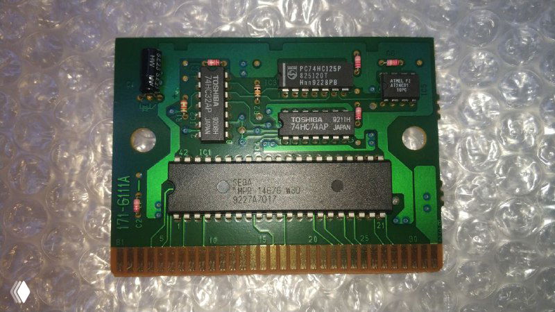 Крупный план печатной платы картриджа: на плате видны микросхемы, включая чип Atmel EEPROM (128 байт) и несколько логических микросхем Toshiba рядом с контактной кромкой.