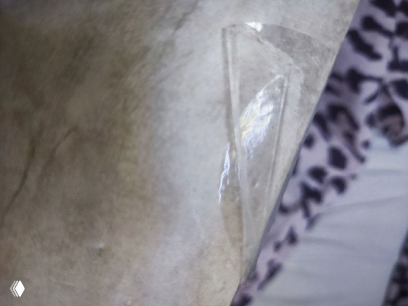 Крупный план повреждённой пломбы на коробке — видно прозрачную клейкую ленту с морщинами и следами неаккуратной запечатки на картонной поверхности.