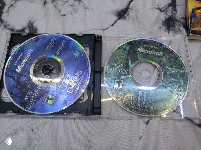 Два компакт-диска из комплекта Collectors Edition: диски расположены рядом в лотках, видно отражающие поверхности и логотип Microsoft на одном из дисков.