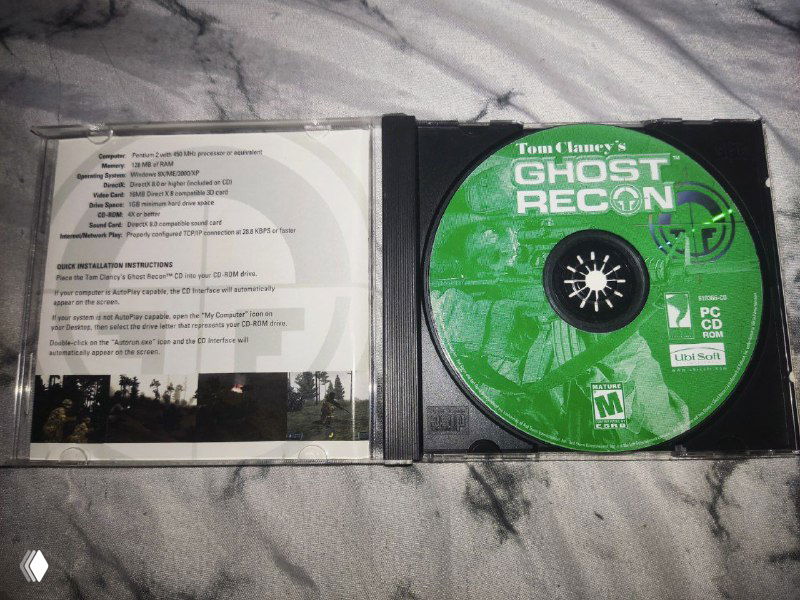 Открытый CD-бокс Ghost Recon: компакт-диск с зелёным принтом и развёрнутый мануал с текстом системных требований внутри конверта.