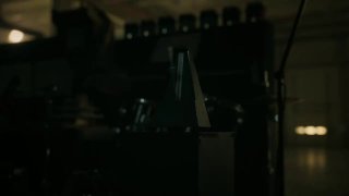 Кадр из рекламного ролика Apple: тёмное индустриальное помещение, крупный план механики и оборудования, атмосферный свет и тень.