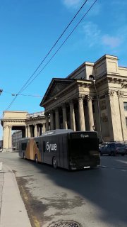 Городской уличный кадр: автобус с брендингом «буше» на фоне классического здания и синего неба; пример визуальной подачи продукта в реальной среде