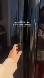 Вертикальный кадр руки, открывающей чёрную дверь большого холодильника/вендинговой машины; на дверце виден текст про стоимость и критику в комментариях.