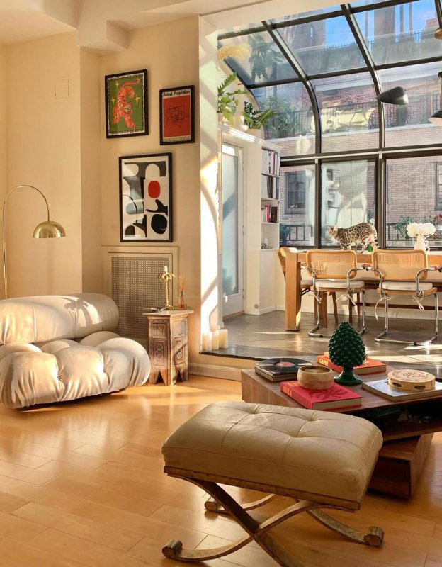 Светлая гостиная с большими окнами, уютной мебелью и отдельной группой плакатов на стене — пример гармонии постеров и интерьера.