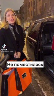 Кадр из ролика: женщина у люксового автомобиля держит большую сумку, на видео текст «Не поместилось» — сценка в развлекательном ключе.