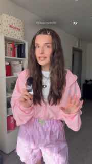 Блогерша в комнате держит товар в руках на фоне полок с книгами; кадр ролика, где акцент сделан на продукте и подаче автора.