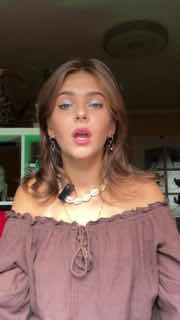 Молодая женщина говорит в камеру в формате вертикального видео, выражая историю об увольнении и переработках в рабочем окружении.