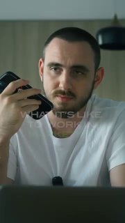 Мужчина держит телефон у уха и смотрит в камеру — сцена из ролика о повседневных задачах агентства и телефонных разговорах с клиентами.