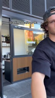 Юноша в кепке на фоне витрины и отражений, прогулочный кадр в ролике о запуске кафе, ощущается уличная атмосфера и ранняя стадия бизнеса.