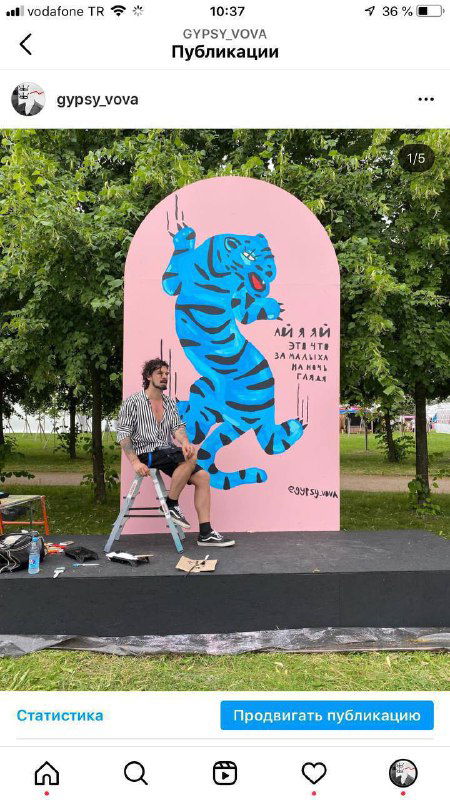 Выступление или площадка на открытом воздухе: большая розовая инсталляция с синим тигром, рядом художник и элементы оформления парка в Санкт-Петербурге.