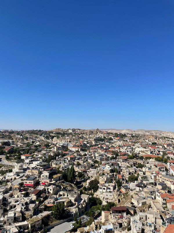 Панорамный вид на город и холмы с высоты; множество домов и куполообразных формаций, ясное голубое небо — пейзаж путешествия и осмотра достопримечательностей.