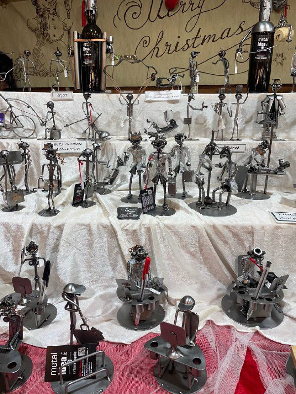 Стол с металлическими фигурками и сувенирами на рождественском базаре: изделия из металла, маленькие фигурки и праздничная витрина.
